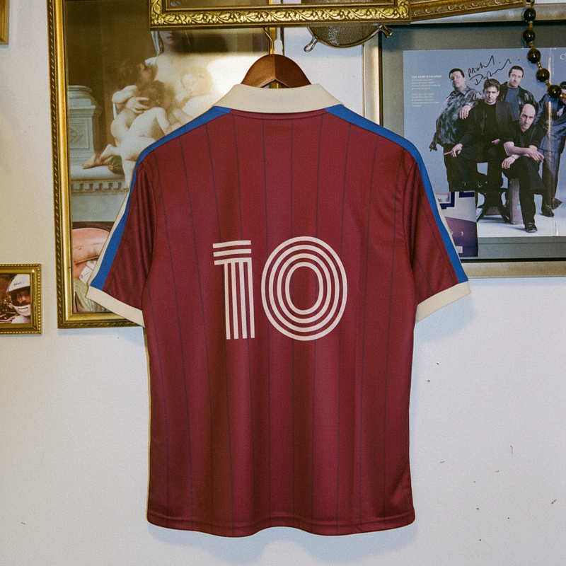 Back of the maroon Ghia Jersey with number 10, hanging against a wall of framed pictures