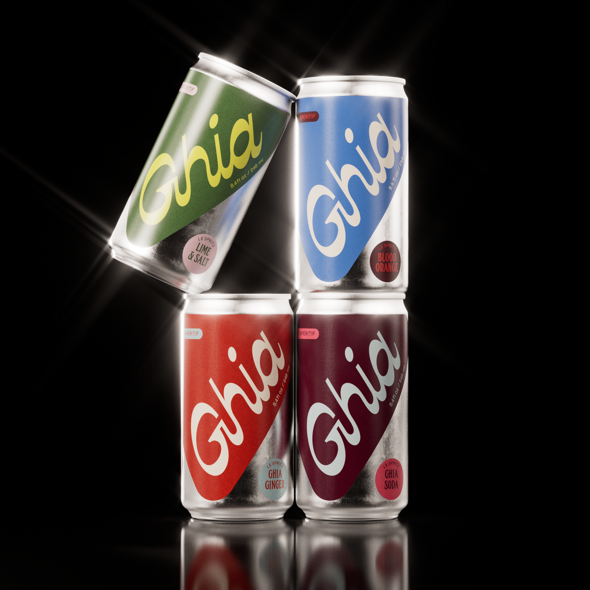 Four Ghia non-alcoholic spritz cans in green, blue, red, and burgundy, featuring Lime & Salt, Blood Orange, Ghia Ginger, and Ghia Soda flavors, stacked against a black background.
