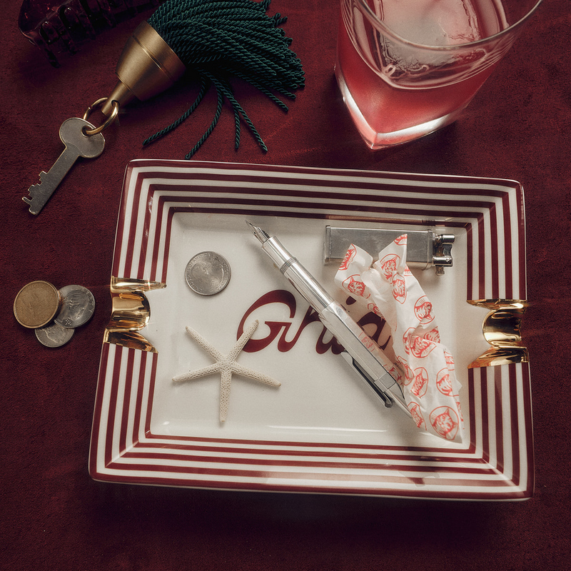 Ghia vide-poche tray on a table holding keys, coins, a starfish, a pen and matches