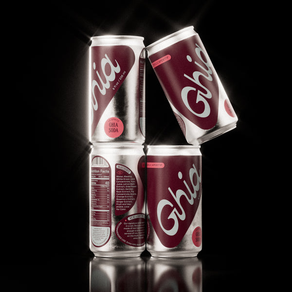 A pack of four Ghia Sumac & Chili non-alcoholic spritz cans stacked in a pyramid formation, with bold white branding, on a glossy black background.