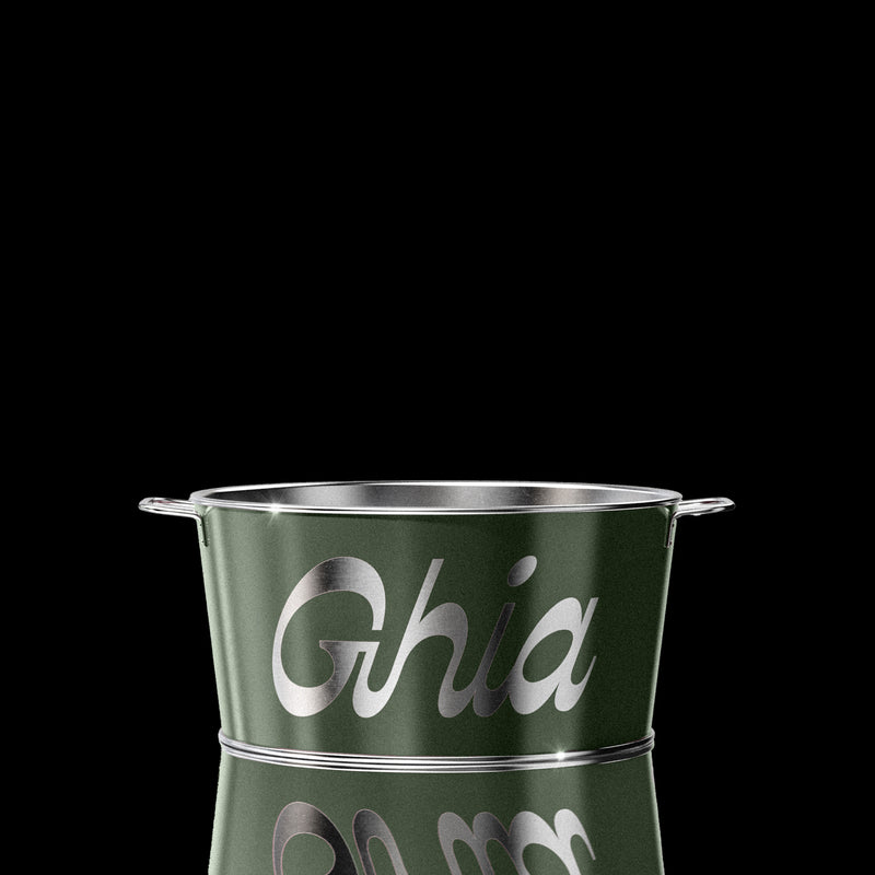 A green Ghia-branded metal ice bucket with silver lettering and handles on both sides, reflecting light on its polished surface.